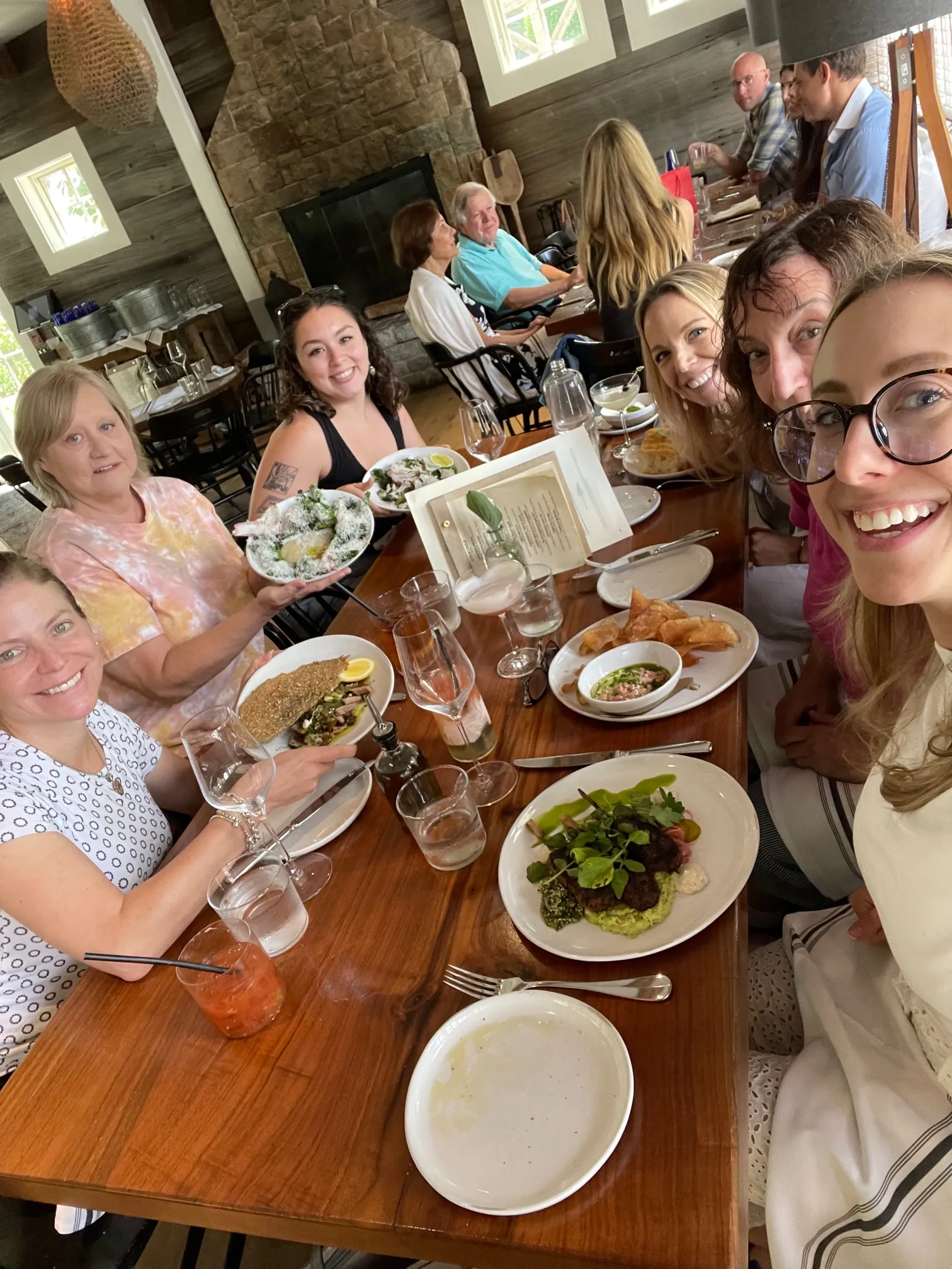 A group smiling around a restaurant table filled with food and drinks.